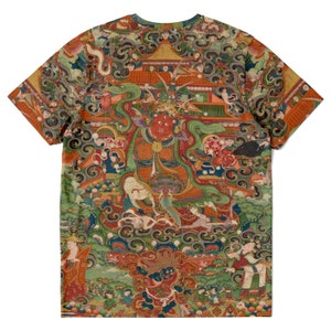 May include: A short-sleeved t-shirt featuring a detailed, colorful illustration. The artwork depicts a central figure with a red face, surrounded by other figures, buildings, and swirling patterns. The design is printed across the entire shirt.