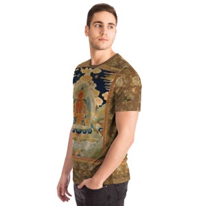 May include: A short-sleeved t-shirt featuring a detailed, colorful illustration of a religious figure. The artwork is set against a dark blue background with floral and cloud motifs. The shirt has a brown collar and sleeves, and a floral pattern on the back.