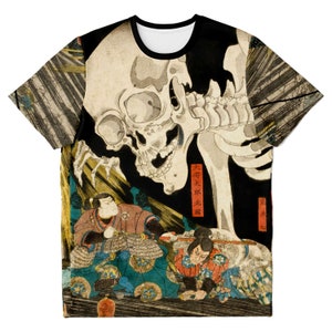 May include: Crew neck t-shirt featuring a Japanese woodblock print with a large skull and figures in traditional clothing. The design includes shades of beige, black, red, and blue. The shirt has a black collar and sleeves.
