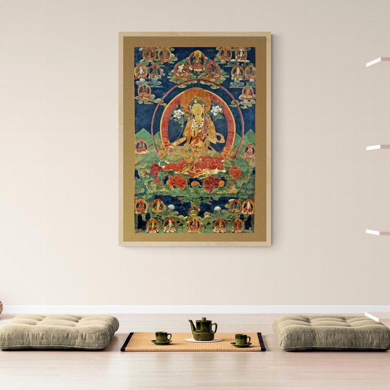 May include: A colorful Tibetan Buddhist thangka painting depicting a deity in a seated position surrounded by smaller figures. The painting is framed in a gold-colored frame.