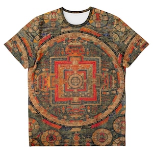 May include: A short-sleeved t-shirt featuring a detailed, colorful mandala design. The artwork incorporates shades of red, orange, brown, and blue, creating a complex and visually striking pattern. The shirt has a white crew neck.