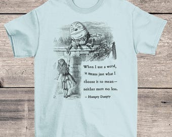 May include: Light blue t-shirt with a black and white illustration of Alice in Wonderland and Humpty Dumpty. The quote "When I use a word, it means just what I choose it to mean - neither more nor less. - Humpty Dumpty" is printed on the shirt.