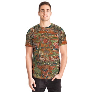 May include: A short-sleeved t-shirt featuring a detailed, colorful illustration. The design includes figures, buildings, and ornate patterns in shades of red, green, orange, and blue. The shirt has a crew neck and a regular fit.