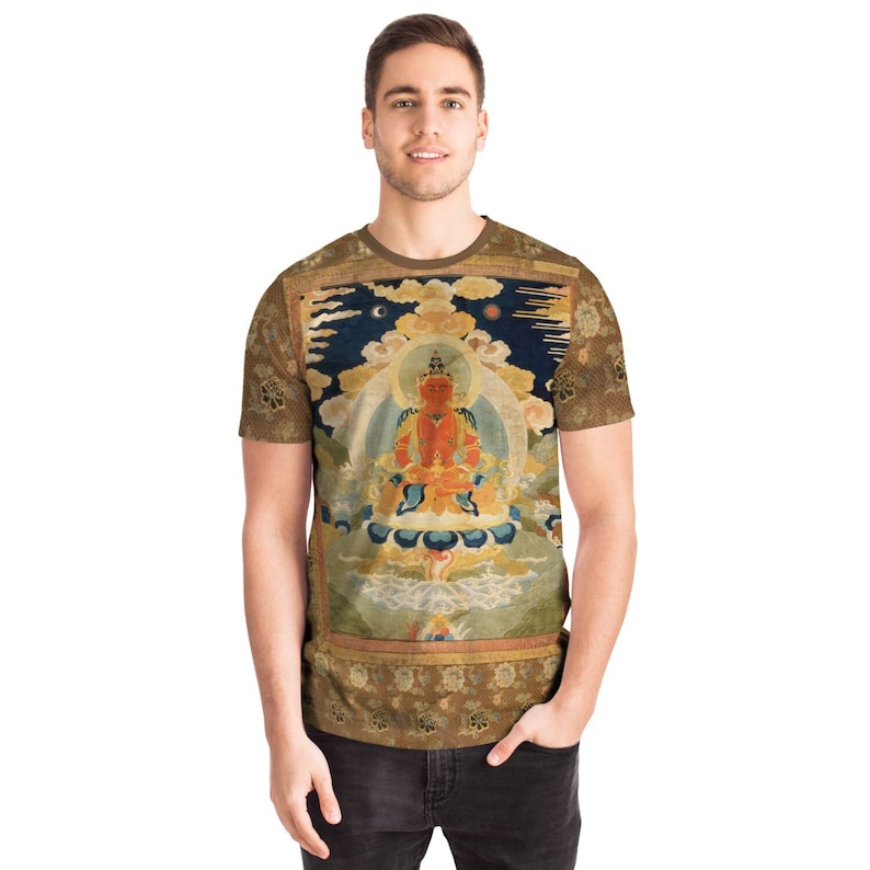 May include: A short-sleeved t-shirt featuring a detailed, colorful illustration of a seated figure with a halo, set against a backdrop of clouds and a night sky. The shirt has a brown border and sleeves with a floral pattern.