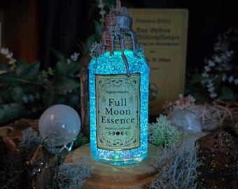May include: A glowing glass bottle labeled "Full Moon Essence" with a teal liquid and a decorative label. The bottle is adorned with moss and sits on a wooden base. The overall aesthetic is mystical and enchanting.
