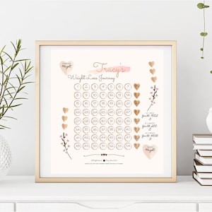 May include: A framed print with a gold frame, titled "Tracy's Weight Loss Journey". It features a grid of numbered circles and heart-shaped markers. Text includes "Starting Weight" and "Target Weight". The print is in a gold frame.