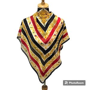 Puede incluir: Un pañuelo cuadrado de seda con un diseño geométrico audaz. El pañuelo presenta rayas alternas en negro, rojo y blanco, acentuadas con filigranas doradas y adornos de tonos joya. El pañuelo se exhibe en un maniquí.