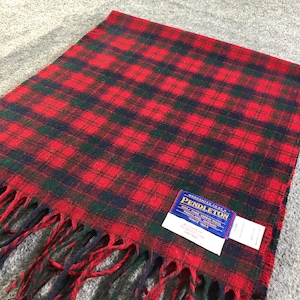 Pode incluir: Cachecol xadrez vermelho, verde e azul marinho com borda com franjas. O cachecol tem uma etiqueta Pendleton. O padrão é um design xadrez clássico, adequado para o clima frio. O cachecol é feito de lã.