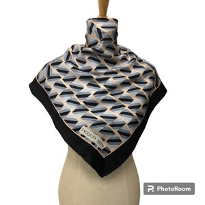 May include: A black and white geometric patterned silk scarf with a black border and the text "JACQUES HEIM" in white.