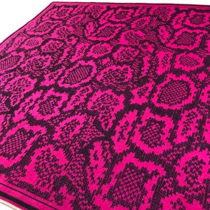 May include: A square scarf featuring a vibrant hot pink and black snakeskin pattern. The fabric displays a repeating reptilian scale design in high contrast colours with a solid black border framing the entire edge of the textile accessory.