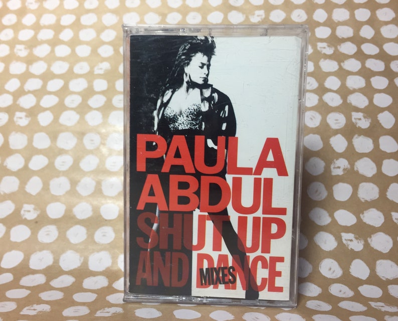 May include: A cassette tape with a red and white design. The tape features a photo of Paula Abdul and the text "Paula Abdul Shut Up And Dance Mixes".