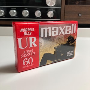 May include: A sealed Maxell UR 60-minute normal bias audio cassette in a red and black plastic case. The packaging features the text Normal Bias, UR, Audio Cassette, 60 Minutes/90m, maxell, and Great For Everyday Recording with a graphic illustration.