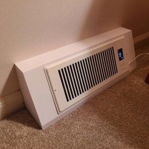 Könnte beinhalten: Weißer, an der Wand montierter Elektroheizkörper mit einem digitalen Display, das 68 Grad Fahrenheit anzeigt. Der Heizkörper hat eine weiße Lüftungsabdeckung mit vertikalen Lamellen.