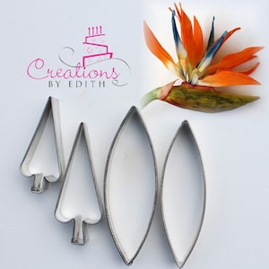 May include: Set of five metal cookie cutters for making bird of paradise flowers. The cutters are silver and include two leaf shapes and three flower shapes.