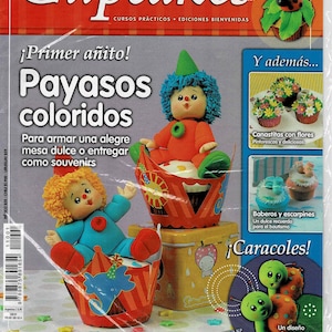 May include: A magazine cover featuring colorful cupcakes decorated with clowns, flowers, and snails. The magazine is titled "Cupcakes" and features the text "Primer añito!" and "Bienvenidas".