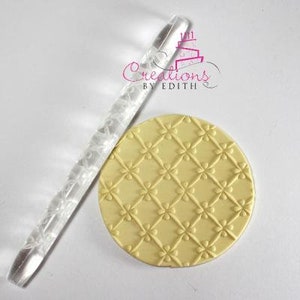May include: A clear acrylic rolling pin with a decorative pattern, and a yellow silicone rolling pin with a diamond and flower pattern. The rolling pin is used for decorating fondant or cookie dough.