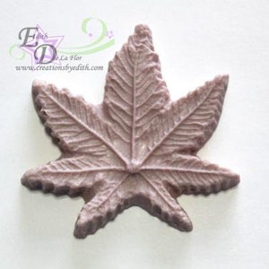 May include: A light pink silicone mold shaped like a maple leaf with detailed veins and a pointed tip.