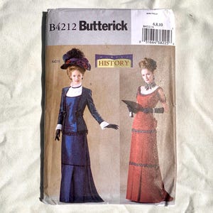 May include: A vintage Butterick sewing pattern, B4212, featuring illustrations of two Edwardian era dresses. The pattern cover displays the text "MAKING HISTORY" and includes size information. The dresses are a dark blue and a red color.