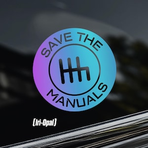 May include: A circular sticker with a gradient of purple and blue, featuring a black gear shift symbol and the text "SAVE THE MANUALS". The sticker also includes the text "[Iri-Opal]" at the bottom. The sticker is affixed to a car window.