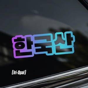 May include: A sticker with the Korean characters for "Made in Korea" in a gradient of purple and blue. The text is outlined in a light blue color. Below the text is the text "[Iri-Opal]" in white.