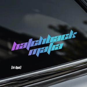 May include: A holographic sticker with the words "hatchback mafia" in a stylized font, shifting from purple to blue. The sticker also features the text "[Iri-Opal]" and a crown logo.