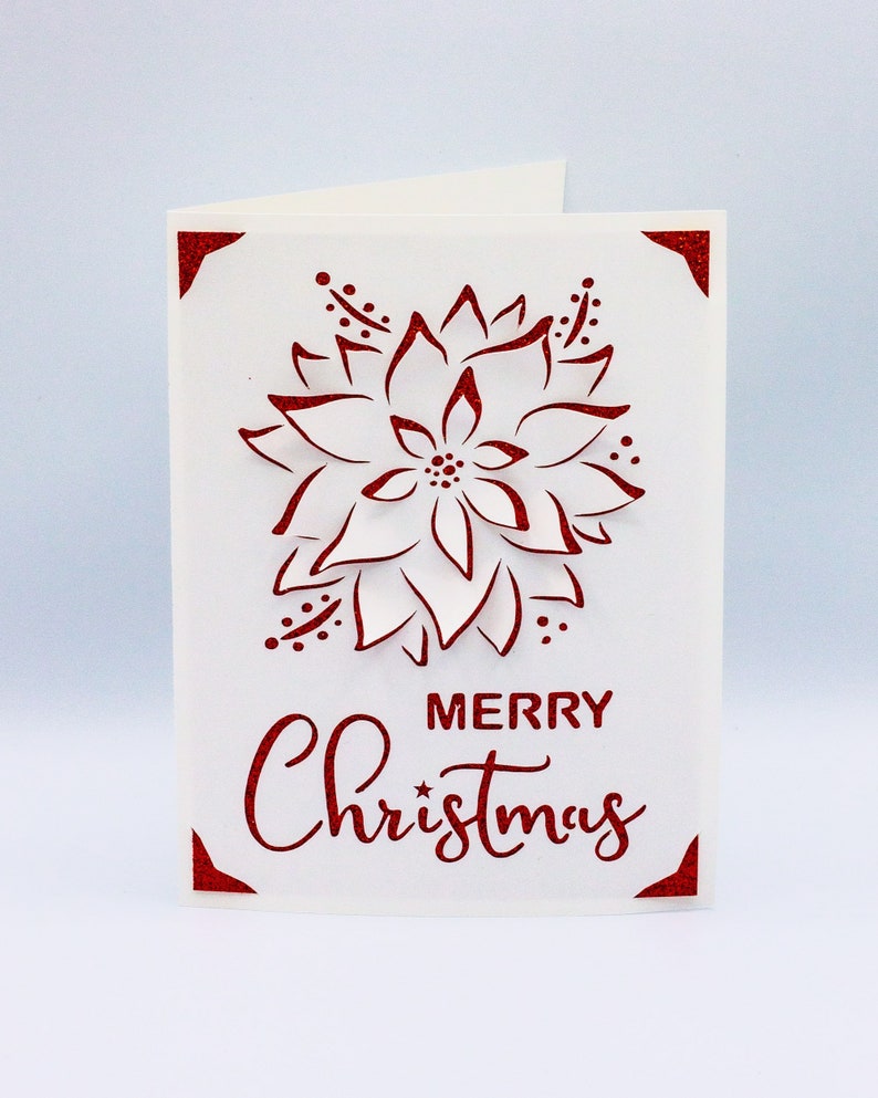 May include: A white card with a red glitter design of a poinsettia flower and the text "Merry Christmas".