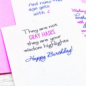 Op de afbeelding: Een witte kaart met een roze kaart erachter. De witte kaart heeft blauwe en roze tekst die luidt "They are not GRAY HAIRS they are your wisdom highlights Happy Birthday!" De roze kaart heeft roze tekst die luidt "Wishing birth with d a c"