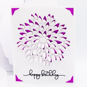 May include: A white card with a pink glitter border and a pink glitter flower design in the center. The card says "happy birthday" in black script.