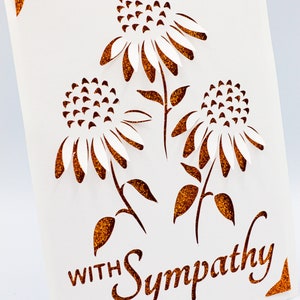 Puede incluir: Una tarjeta blanca con un mensaje de condolencias en letras de purpurina marr&oacute;n. La tarjeta presenta un dise&ntilde;o recortado de tres flores blancas con tallos y hojas de purpurina marr&oacute;n.
