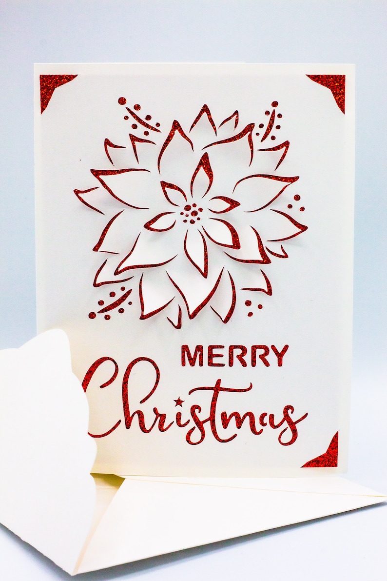 May include: A white card with a red glitter design of a poinsettia flower and the text "Merry Christmas".