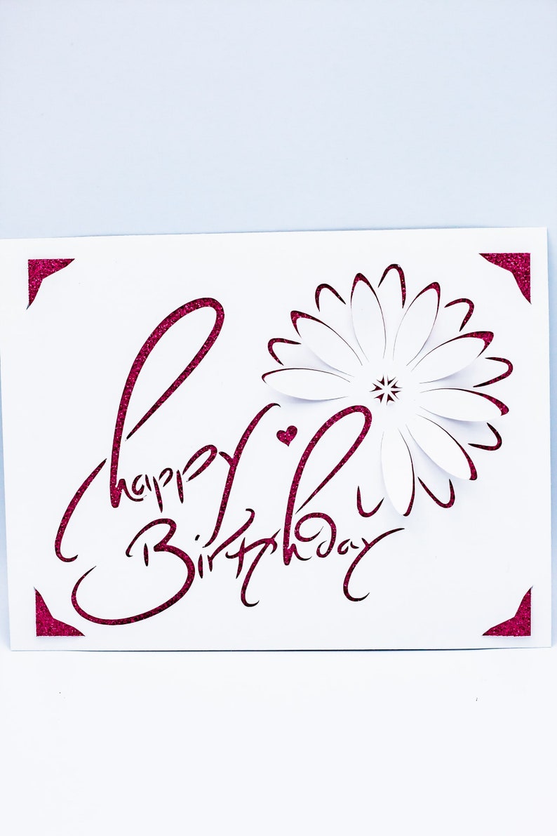 May include: A white card with a pink glitter design that says "Happy Birthday" with a pink heart and a pink outline of a flower.