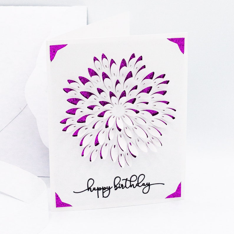 May include: White card with a purple glitter border and a white paper flower with purple glitter edges. The card says "happy birthday" in black script.