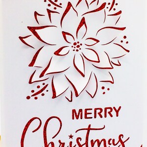 May include: A white card with a red glitter border and a red glitter poinsettia design. The card says "Merry Christmas" in red glitter.