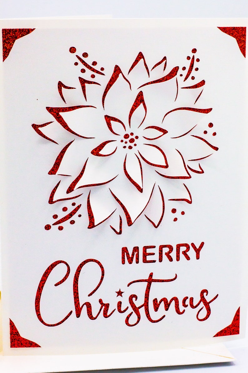 May include: A white card with a red glitter border and a red glitter poinsettia design. The card says "Merry Christmas" in red glitter.