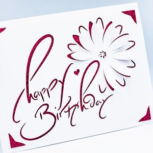 May include: A white card with a pink glitter design that says "Happy Birthday" with a pink glitter flower in the corner.