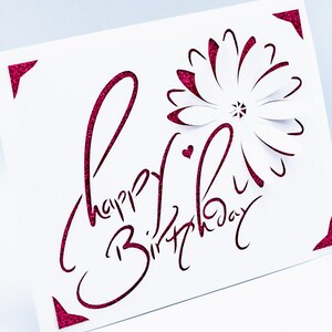 May include: A white card with a pink glitter border and a pink glitter cut-out design that says "Happy Birthday" with a flower in the center.