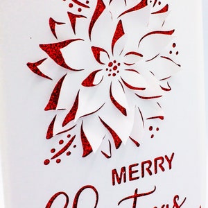 May include: A white card with a red glitter poinsettia design and the text "Merry Christmas" in red glitter.
