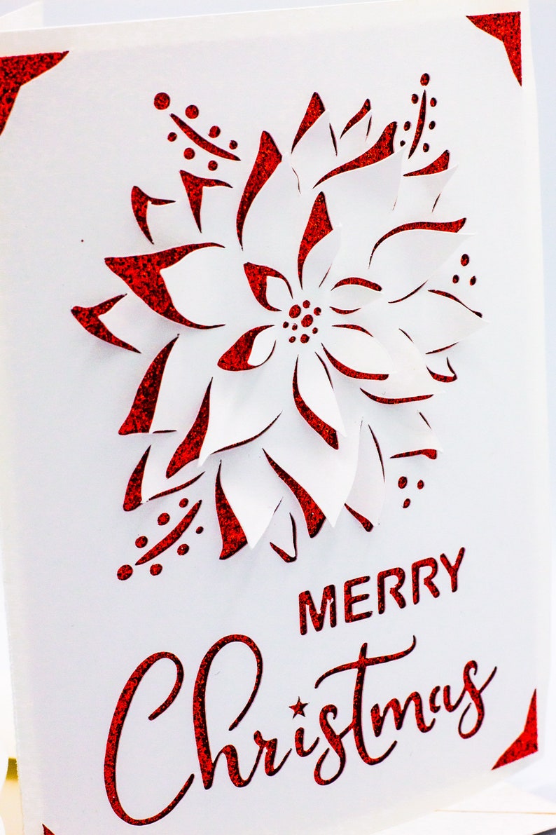 May include: A white card with a red glitter poinsettia design and the text "Merry Christmas" in red glitter.