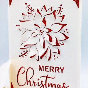 May include: A white card with a red glitter border and a red glitter poinsettia design. The card says "Merry Christmas" in red glitter.
