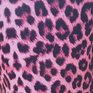 Puede incluir: Primer plano de una tela con estampado de leopardo rosa y negro. El patr&oacute;n presenta manchas negras oscuras sobre un fondo rosa claro. La tela parece suave y podr&iacute;a usarse para ropa o accesorios.