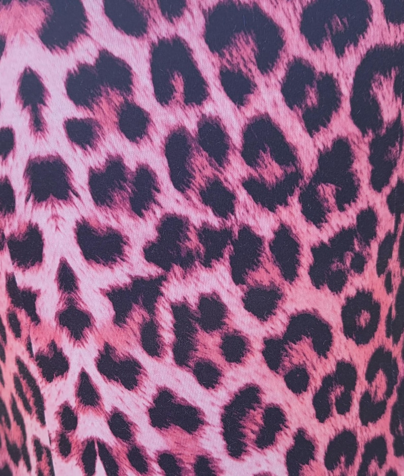 Puede incluir: Primer plano de una tela con estampado de leopardo rosa y negro. El patr&oacute;n presenta manchas negras oscuras sobre un fondo rosa claro. La tela parece suave y podr&iacute;a usarse para ropa o accesorios.
