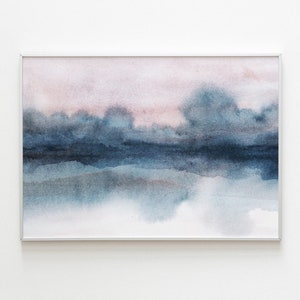K&ouml;nnte beinhalten: Abstrakte Aquarellmalerei in Blaut&ouml;nen und Rosa, die eine Landschaft mit einem Horizont und Wolken darstellt. Das Gem&auml;lde ist in einem wei&szlig;en Rahmen gerahmt.
