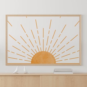 以下が含まれることがあります： 木製のキャビネット、フロアランプ、鉢植えの植物があるミニマルなリビングルームのインテリア。スタイリッシュな太陽と光線が描かれた額縁付きのプリントが壁に飾られています。