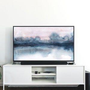 K&ouml;nnte beinhalten: Ein Flachbildfernseher mit schwarzem Rahmen und einem Standfu&szlig;. Der Fernseher zeigt ein abstraktes Aquarellbild einer blauen und rosa Landschaft.