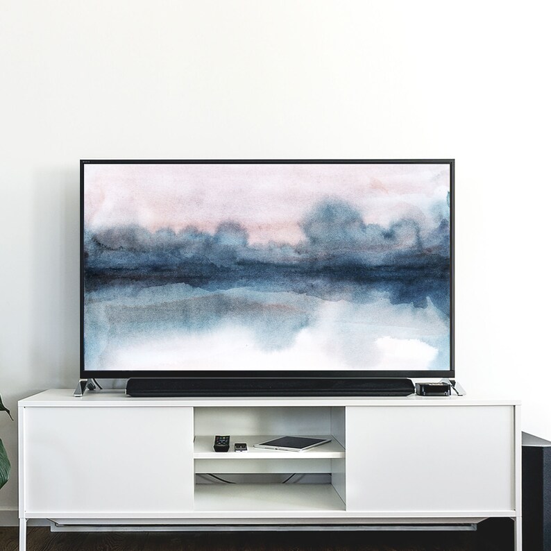 K&ouml;nnte beinhalten: Ein Flachbildfernseher mit schwarzem Rahmen und einem Standfu&szlig;. Der Fernseher zeigt ein abstraktes Aquarellbild einer blauen und rosa Landschaft.