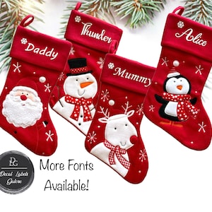 May include: A collection of red Christmas stockings, each with a name embroidered in white. Designs include Santa, a snowman, a reindeer, and a penguin. The stockings are decorated with snowflakes. The text "Daddy", "Thunder", "Mummy", and "Alice" are displayed. The text "More Fonts Available!" is also displayed.