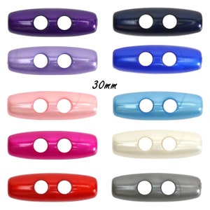 May include: Assortment of 10 plastic toggle buttons in various colours, each measuring 30mm in length. The buttons have two holes and a shiny finish.