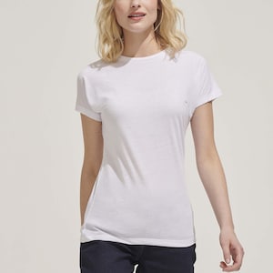 Op de afbeelding: Een wit T-shirt met korte mouwen en een ronde hals. Het model draagt het T-shirt met een donkerblauwe jeans.