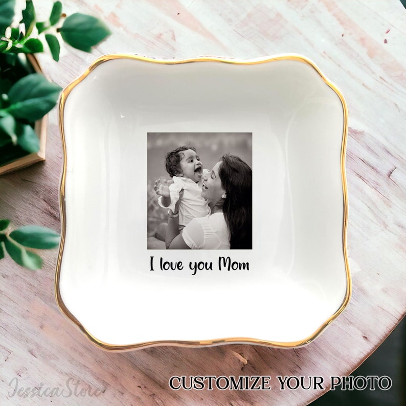 Puede incluir: Bandeja de cer&aacute;mica blanca con borde dorado. La bandeja presenta una foto en blanco y negro de una madre y un hijo con el texto "Te amo mam&aacute;".