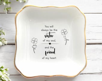Op de afbeelding: Een vierkant wit keramieken schaaltje met een goudkleurige, geschulpte rand. In het midden staat de zwarte tekst: You will always be the sister of my soul, and the friend of my heart, geflankeerd door twee klaverillustraties met namen.